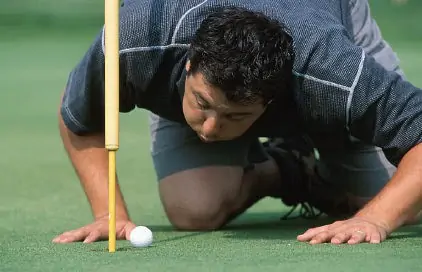 Golfspieler bläst den Golfball ins Loch