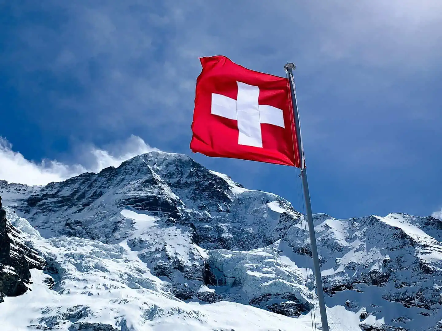Schweizer Flagge vor Bergen mit Schnee