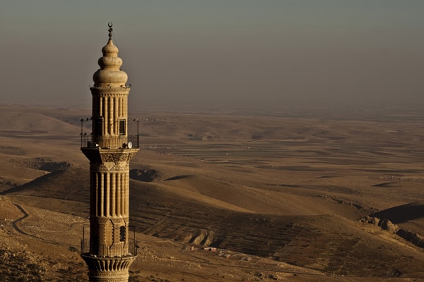 Türkei auswandern - fremde Kultur: Minarett einer Moschee, im Hintergrund braunes Hügelland.