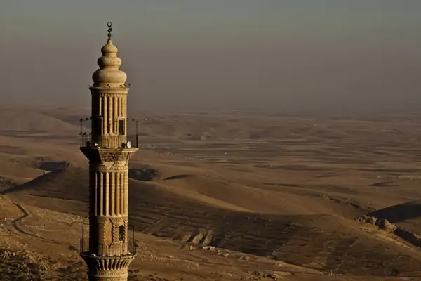 Türkei auswandern - fremde Kultur: Minarett einer Moschee, im Hintergrund braunes Hügelland.